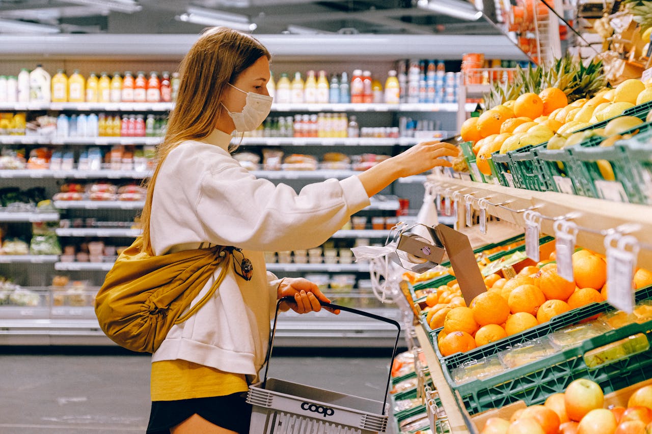 A woman wearing a mask shops for fruits at a supermarket, ensuring personal protection during the pandemic.