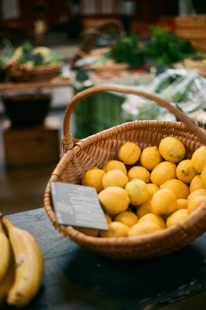 A basket of bright yellow lemons on display at a fresh produce market.
